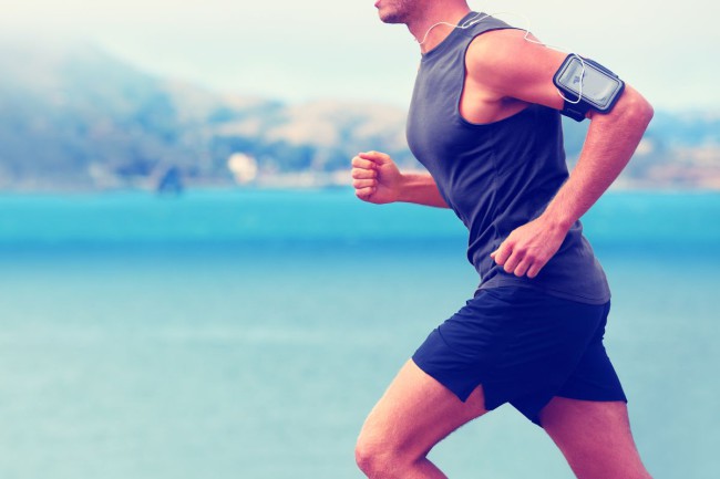 Cardio runner running listening smartphone music. Unrecognizable